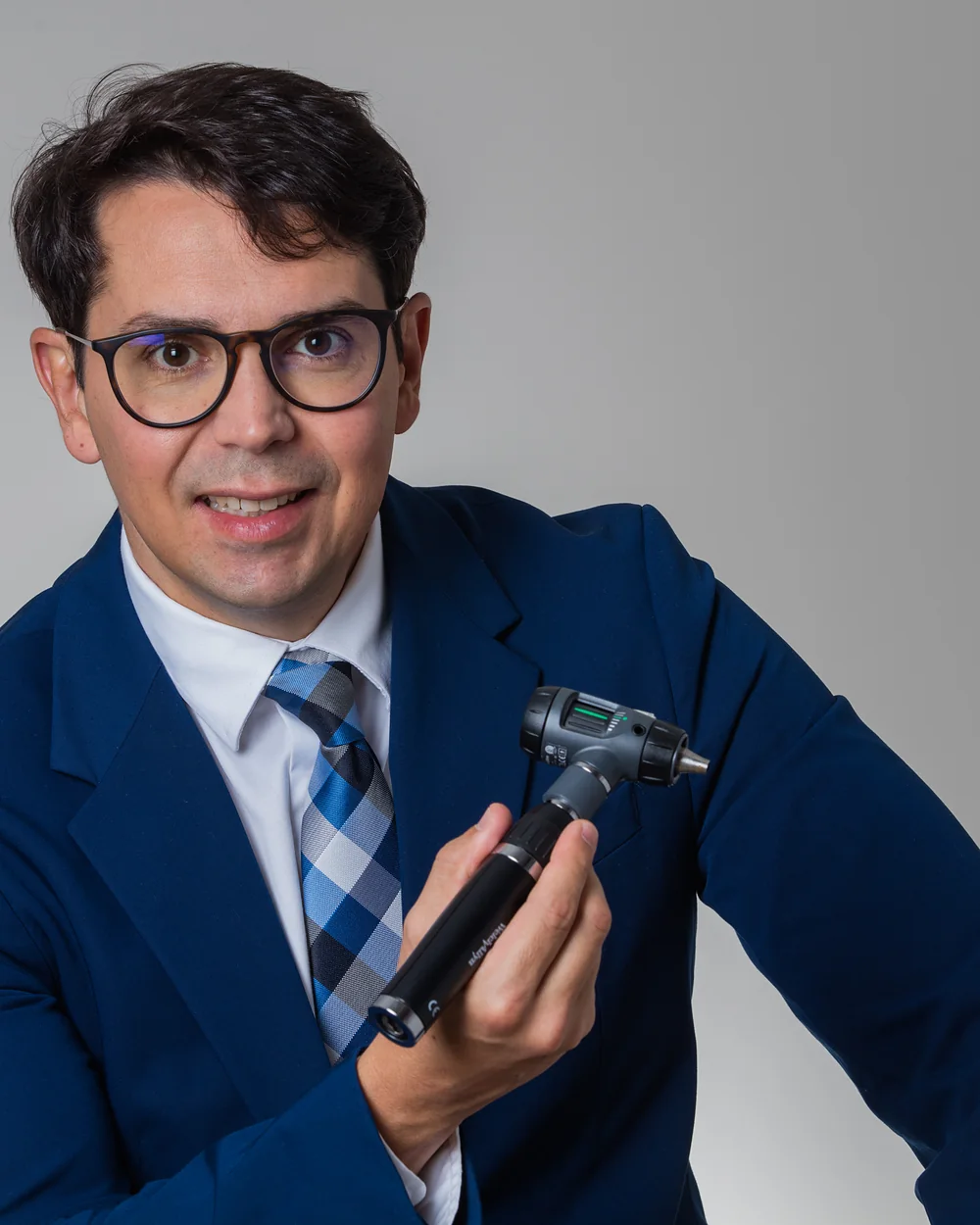 Dr. Gustavo Lara Rezende, de terno azul, segurando um otoscópio
